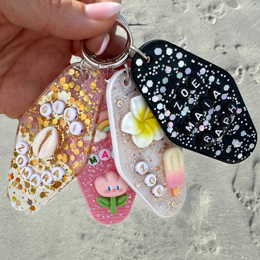 Porte-clé artisanal en résine, personnalisé avec des paillettes, des lettres et des breloques.