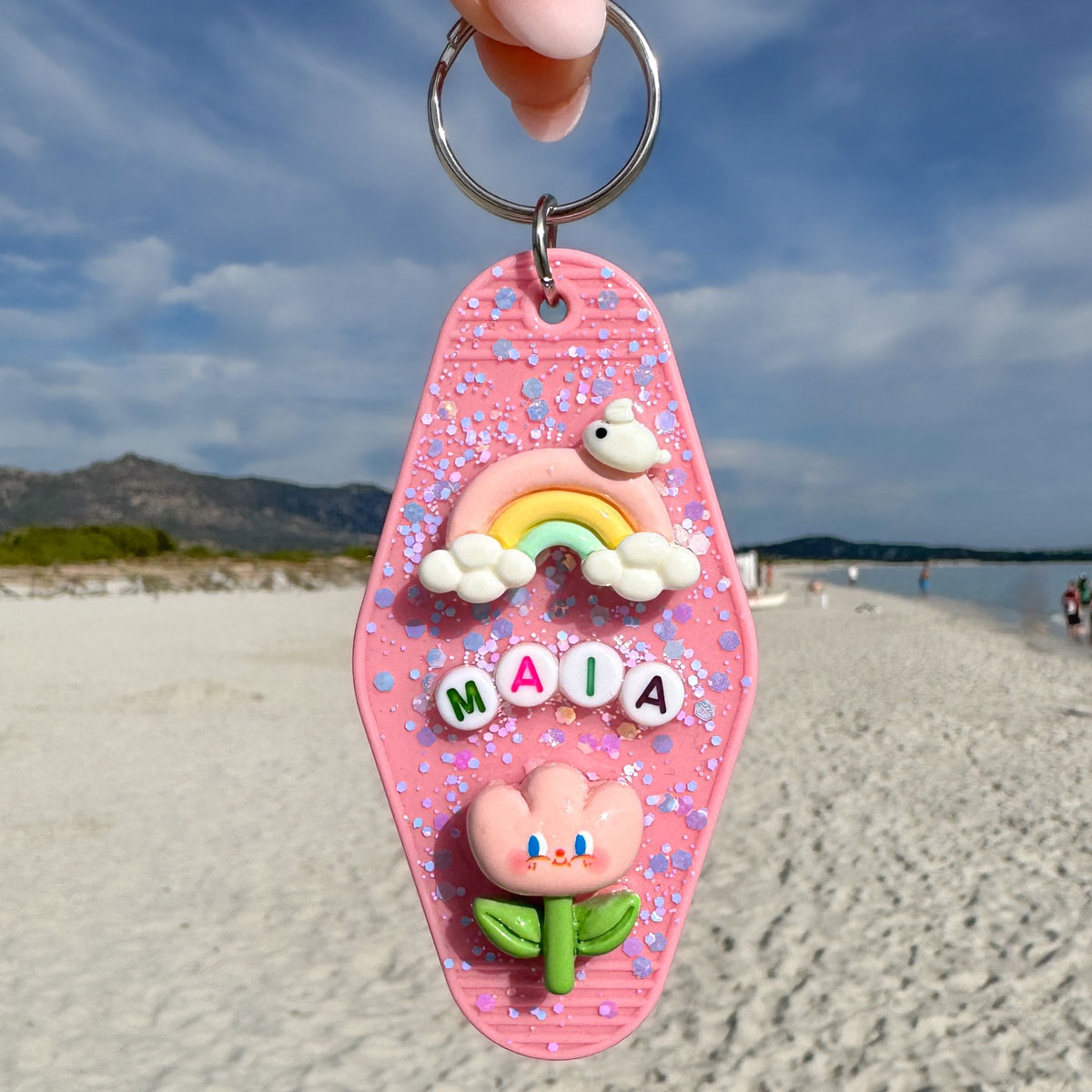 Porte-clé artisanal en résine rose, à personnaliser avec des breloques, des lettres et des paillettes.